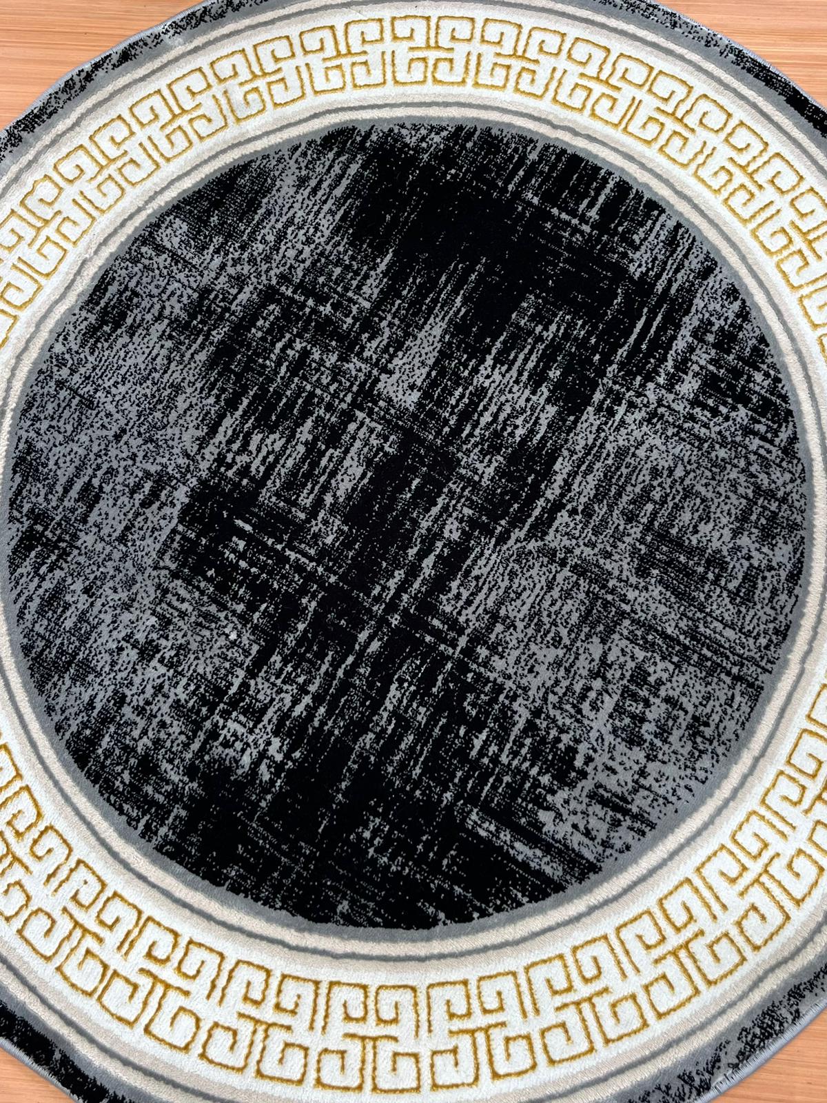 Round black rug with gold geometric patterns on a wooden floor