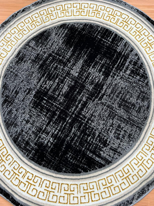Round black rug with gold geometric patterns on a wooden floor